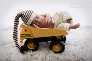 Newborn baby boy in toy dumper truck